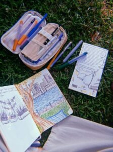 A notebook and pencils on the grass